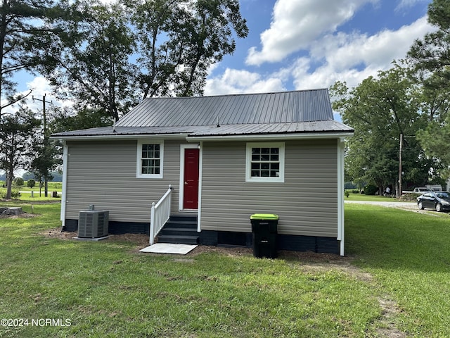 rear view of house featuring a lawn and central AC unit