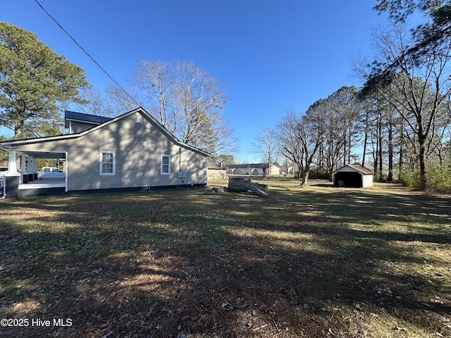 view of side of home featuring a yard, a carport, and a storage unit