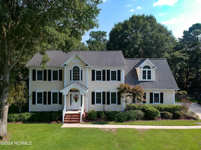 colonial-style house with a shingled roof and a front yard