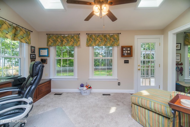 office space featuring ceiling fan, a wealth of natural light, carpet, and vaulted ceiling with skylight