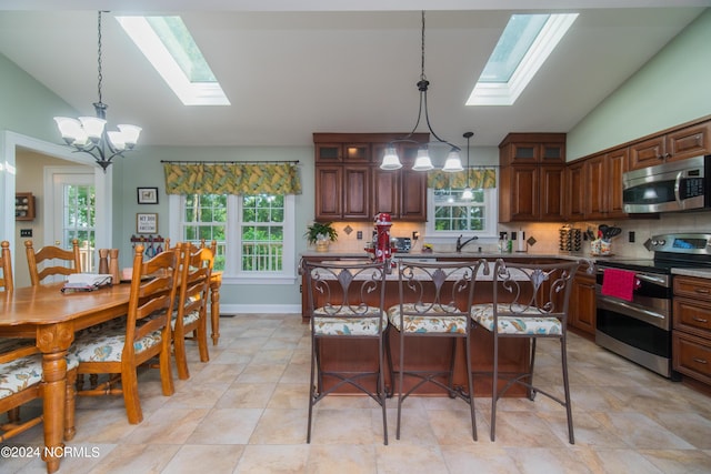 kitchen with tasteful backsplash, a skylight, light tile patterned flooring, and stainless steel appliances