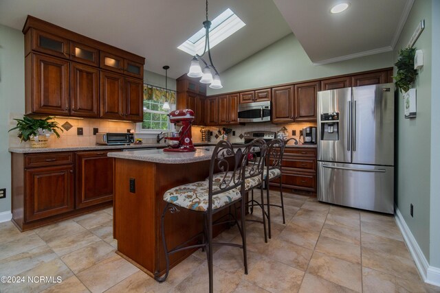 kitchen featuring stainless steel appliances, lofted ceiling with skylight, pendant lighting, a breakfast bar area, and a center island