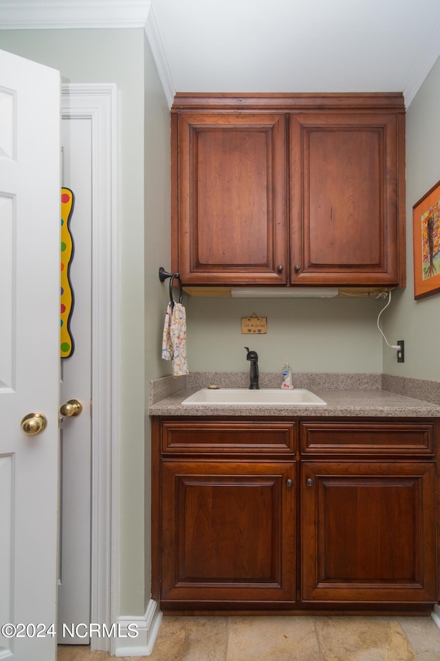 kitchen with sink, light tile patterned floors, and ornamental molding