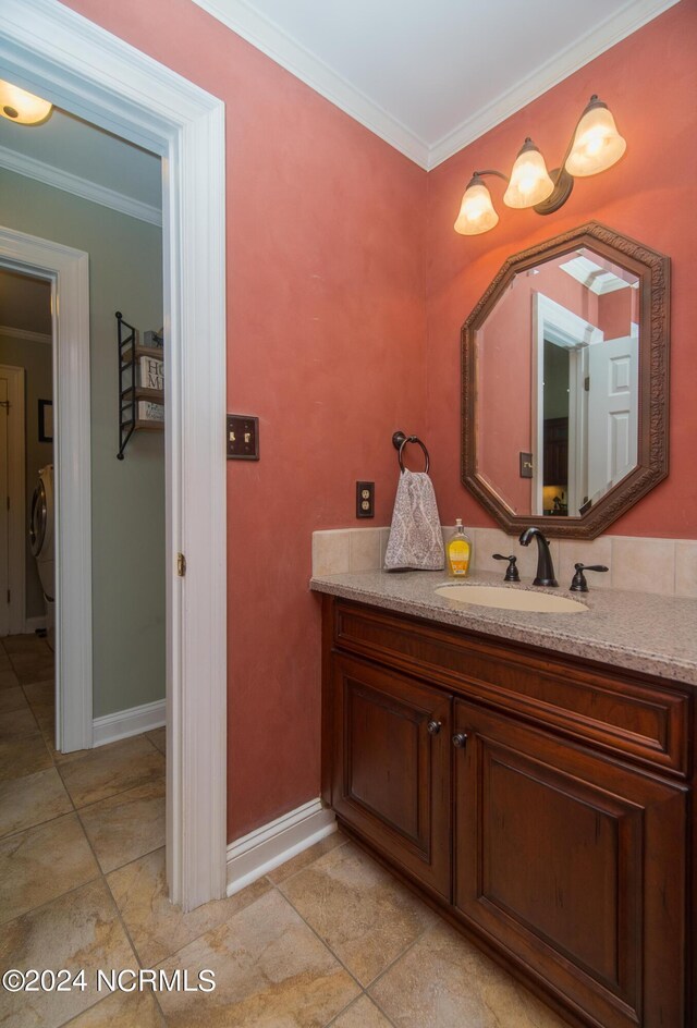 bathroom with tile patterned flooring, vanity, washer / dryer, and ornamental molding