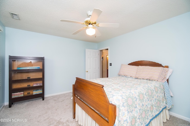 bedroom with a textured ceiling, ceiling fan, and light carpet