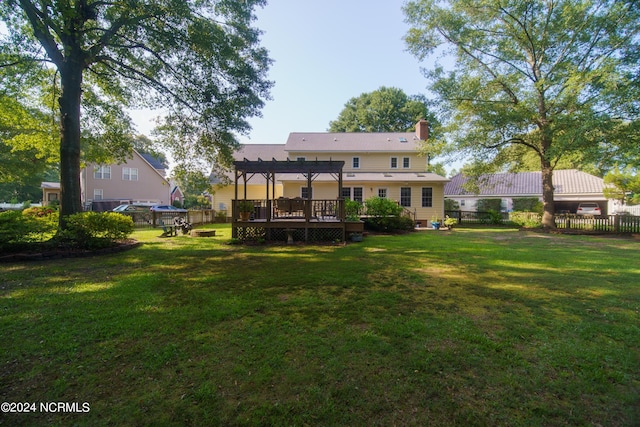 rear view of house with a deck, a pergola, and a lawn