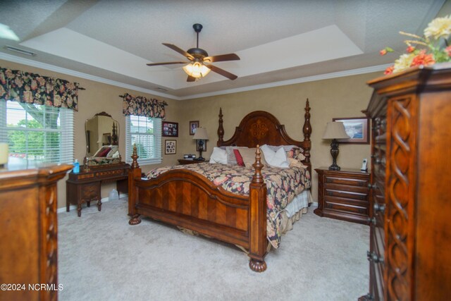 carpeted bedroom with ceiling fan, a raised ceiling, and ornamental molding