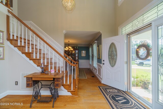 foyer entrance featuring light wood-type flooring, a towering ceiling, and an inviting chandelier