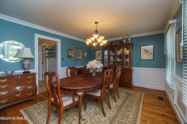 dining area with ornamental molding, hardwood / wood-style floors, and an inviting chandelier