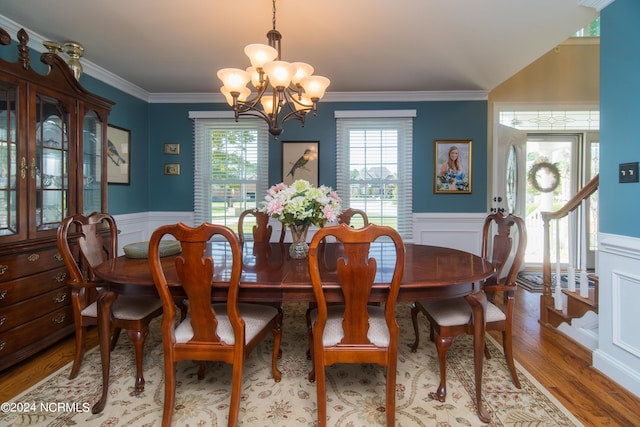 dining space with hardwood / wood-style flooring, an inviting chandelier, and crown molding