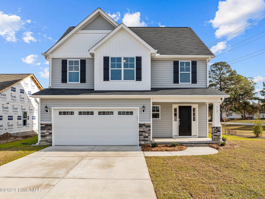 view of front of home featuring covered porch, a garage, and a front yard