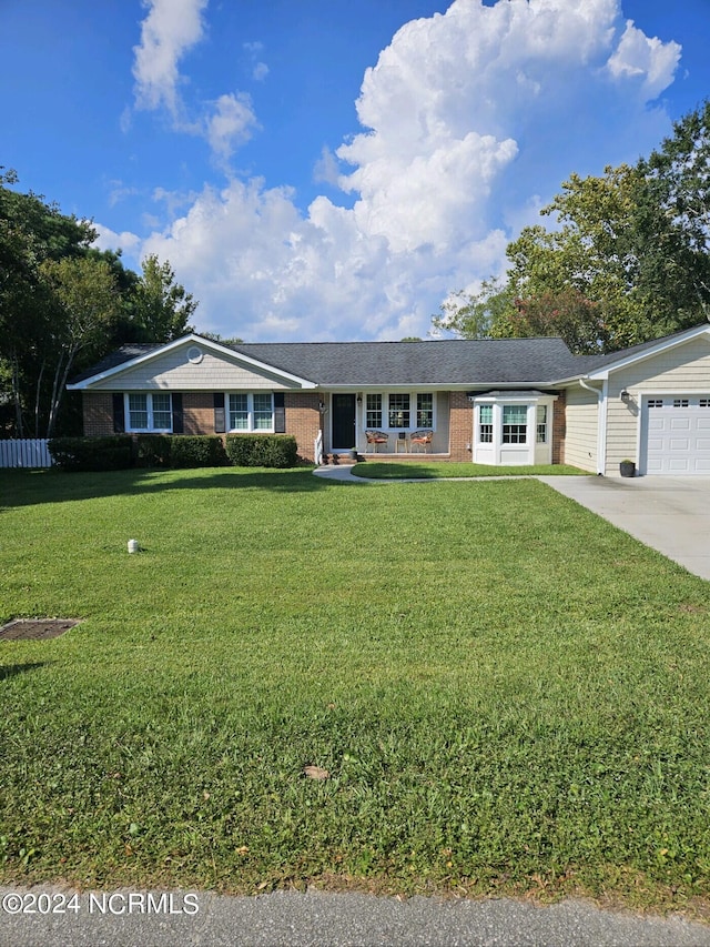 single story home featuring a garage, concrete driveway, brick siding, and a front yard