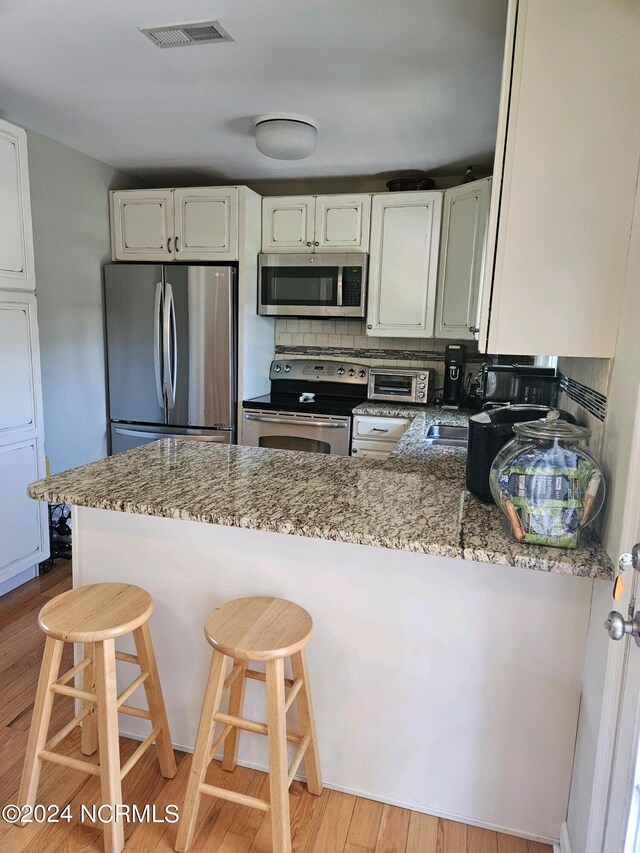 kitchen featuring kitchen peninsula, light stone countertops, and appliances with stainless steel finishes