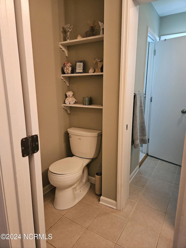 bathroom featuring toilet, baseboards, and tile patterned floors