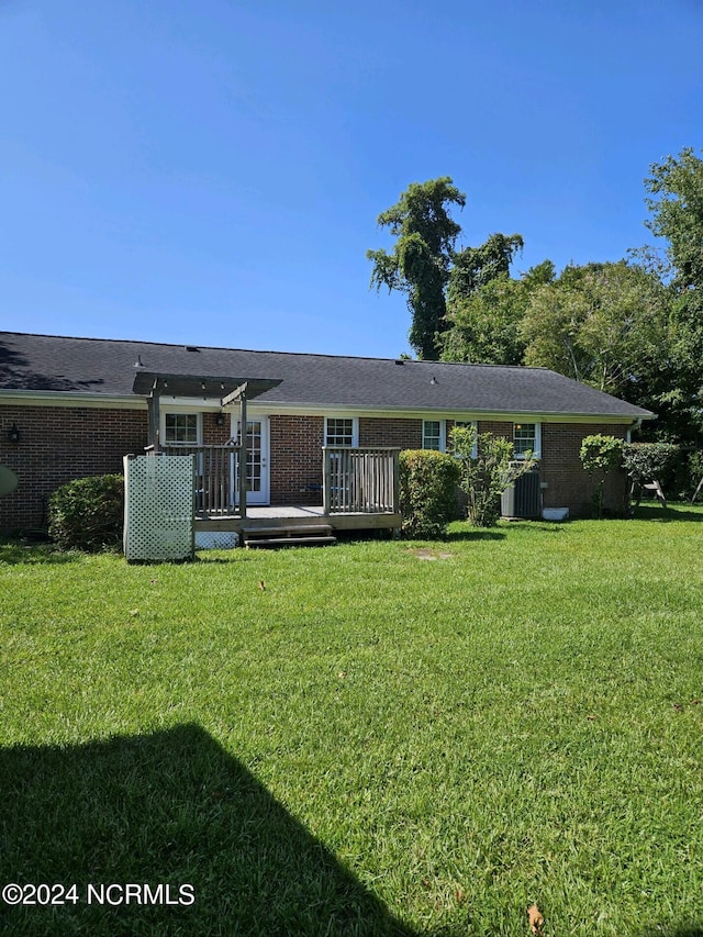 back of house featuring brick siding, a lawn, and a deck