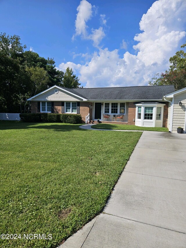 ranch-style home featuring covered porch and a front lawn