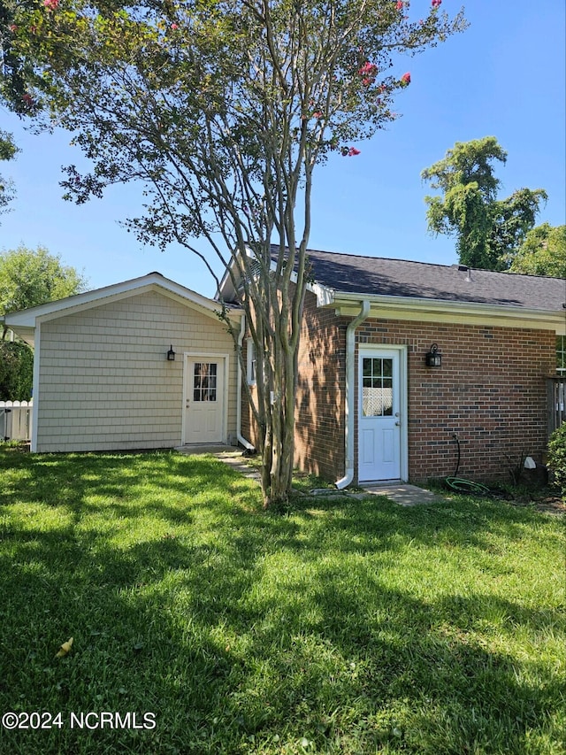 rear view of house featuring brick siding and a yard