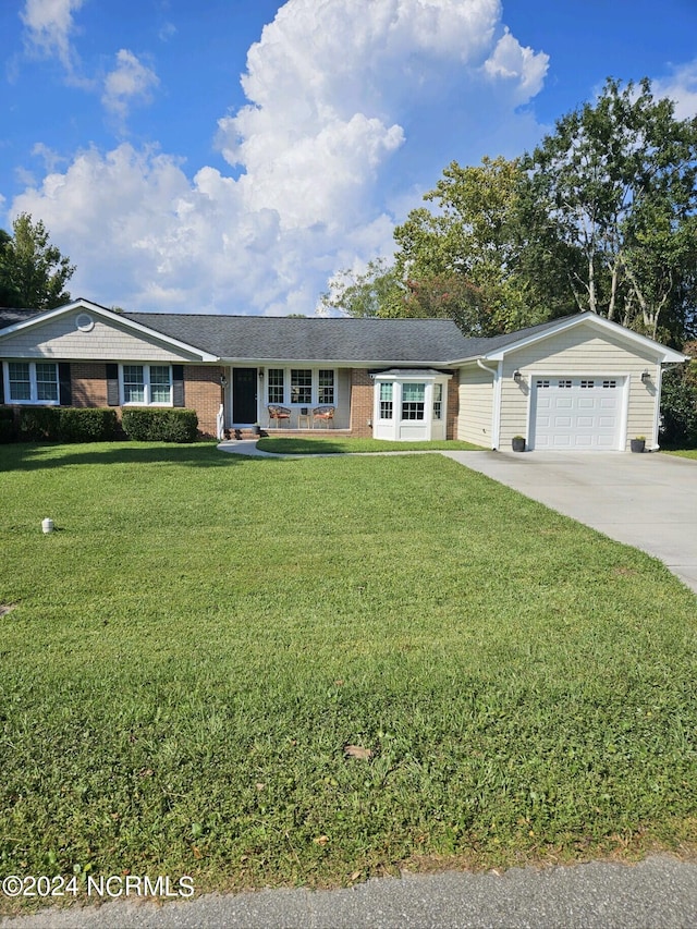 ranch-style house featuring driveway, brick siding, an attached garage, and a front yard