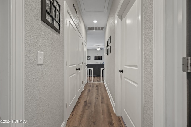 hallway with visible vents, dark wood-type flooring, and a textured wall