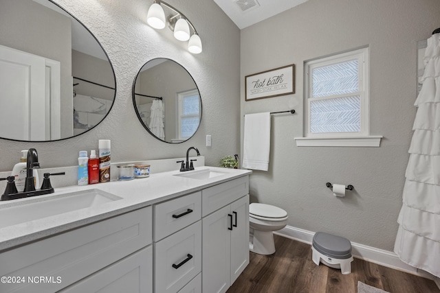 bathroom featuring toilet, wood finished floors, visible vents, and a sink