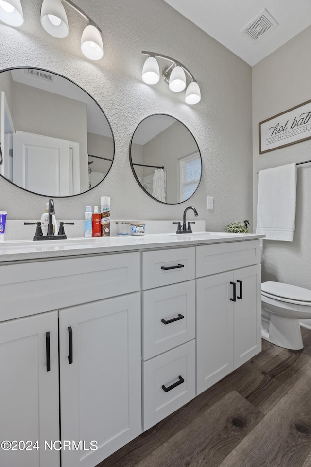 full bathroom with visible vents, toilet, a shower with curtain, wood finished floors, and double vanity