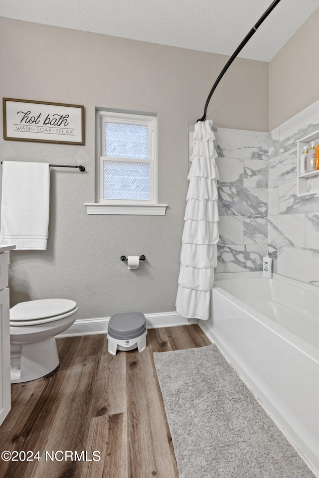 bathroom with baseboards, shower / tub combo with curtain, wood finished floors, and toilet