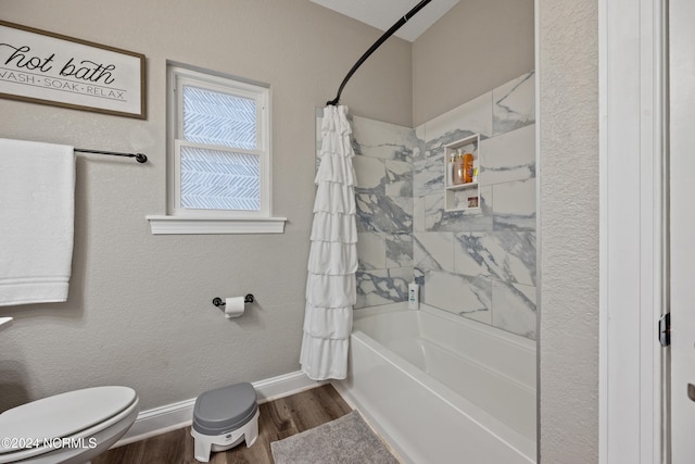 bathroom with toilet, wood finished floors, shower / bath combo, and baseboards