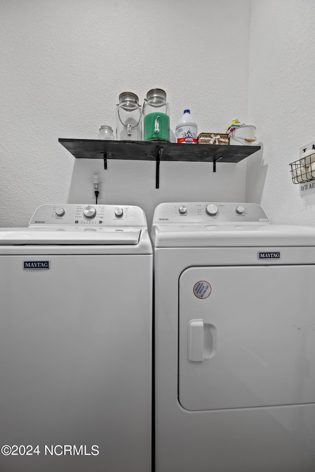 washroom with laundry area, washing machine and dryer, and a textured wall