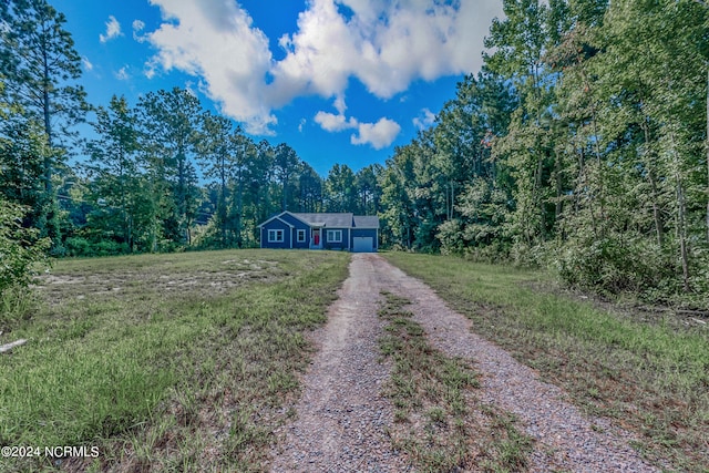 view of front of house featuring a front lawn, an attached garage, a view of trees, and driveway