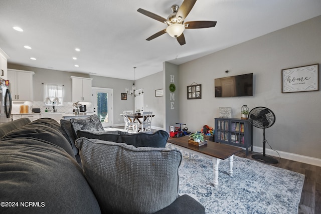 living area with recessed lighting, ceiling fan with notable chandelier, dark wood-type flooring, and baseboards