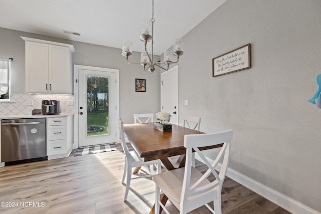 dining room featuring light wood-style flooring, a notable chandelier, baseboards, and visible vents