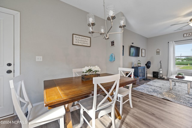 dining room with baseboards, wood finished floors, and ceiling fan with notable chandelier