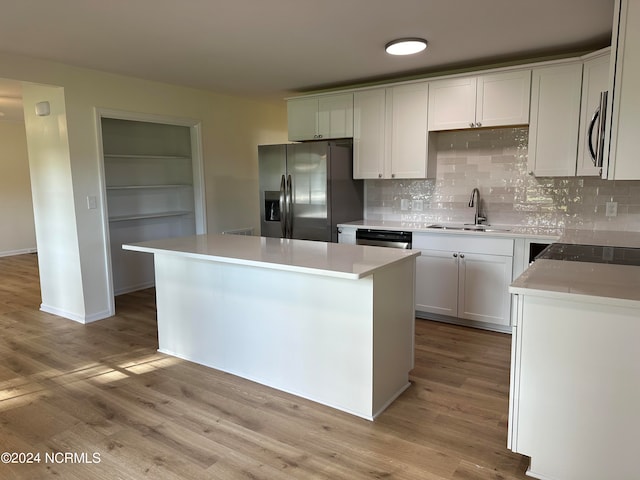 kitchen with a kitchen island, tasteful backsplash, light hardwood / wood-style floors, stainless steel appliances, and sink