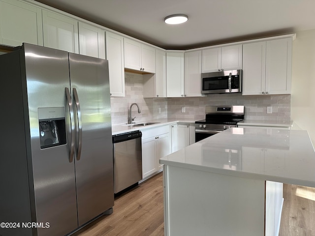 kitchen featuring light hardwood / wood-style flooring, stainless steel appliances, sink, light stone counters, and white cabinets