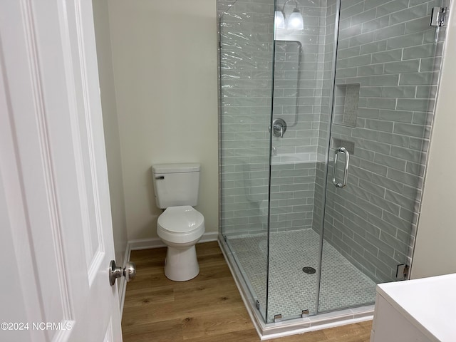 bathroom featuring walk in shower, toilet, hardwood / wood-style flooring, and vanity