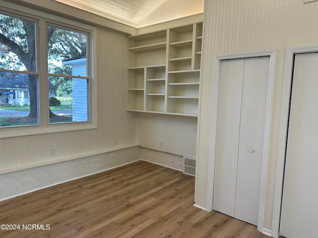 unfurnished bedroom featuring wood walls and wood-type flooring