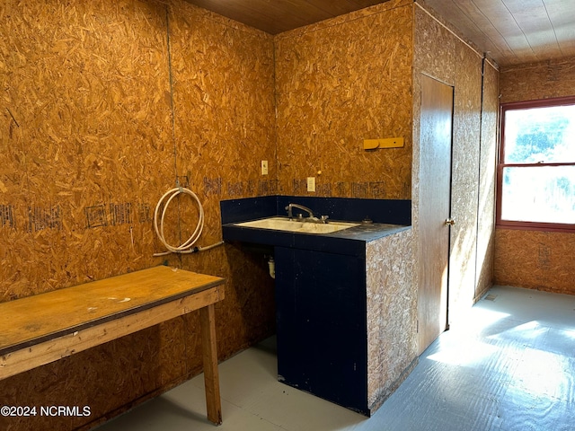 bathroom featuring wood ceiling, sink, and wooden walls