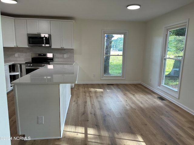 kitchen with white cabinetry, light hardwood / wood-style flooring, stainless steel appliances, and decorative backsplash