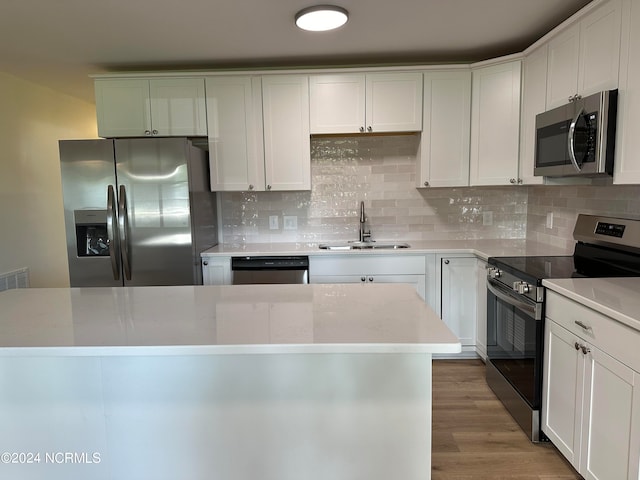 kitchen with wood-type flooring, stainless steel appliances, white cabinetry, and sink