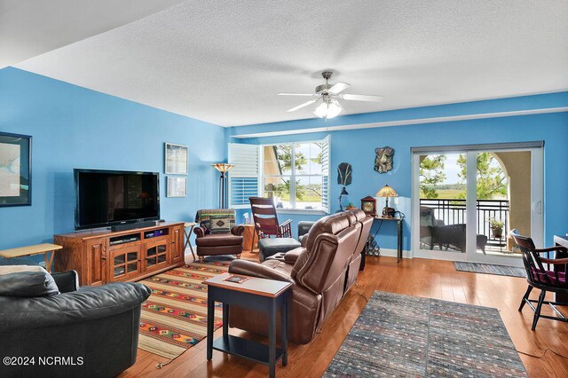 living room featuring ceiling fan, a textured ceiling, and light hardwood / wood-style flooring