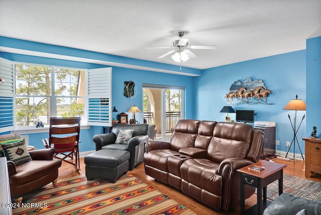 living room with a textured ceiling, wood-type flooring, and ceiling fan