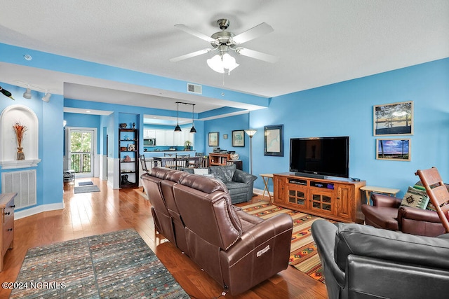 living room featuring wood-type flooring and ceiling fan