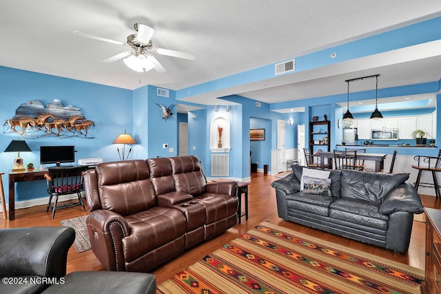 living room featuring a textured ceiling, hardwood / wood-style flooring, and ceiling fan