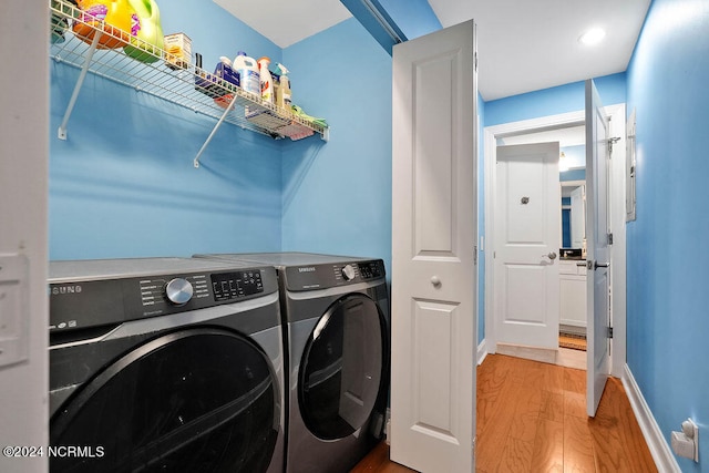 clothes washing area with hardwood / wood-style floors and washing machine and dryer