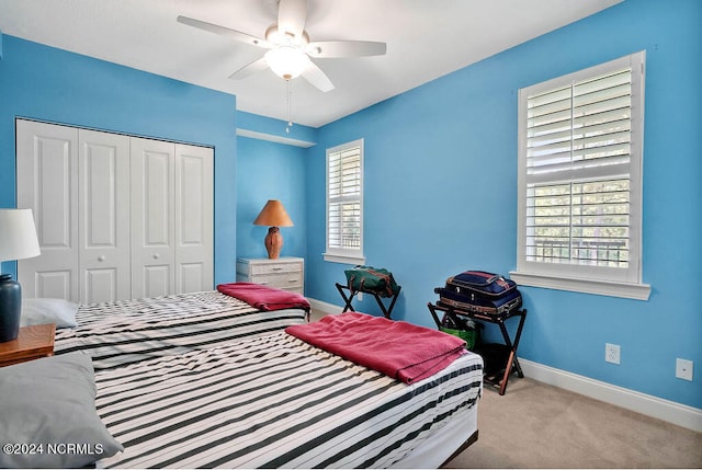 bedroom featuring ceiling fan, light carpet, and a closet