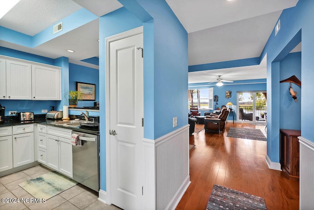 kitchen with stainless steel dishwasher, light hardwood / wood-style floors, white cabinets, and sink