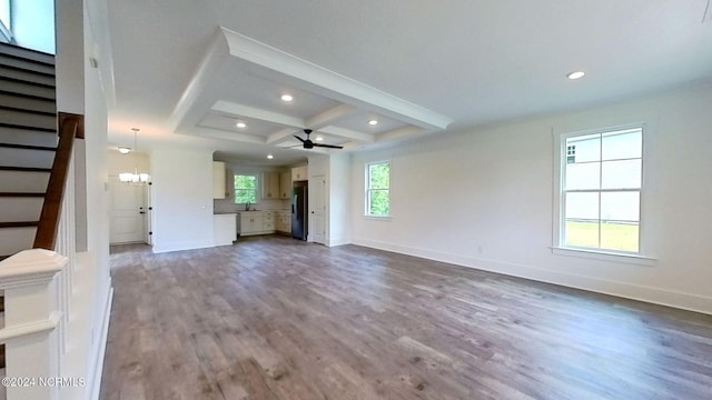 unfurnished living room with wood-type flooring, sink, ceiling fan with notable chandelier, coffered ceiling, and beam ceiling