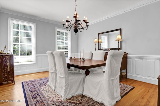 dining area featuring light wood-type flooring, a notable chandelier, and crown molding