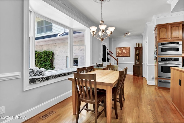 dining area featuring crown molding, a notable chandelier, light wood-type flooring, and a fireplace