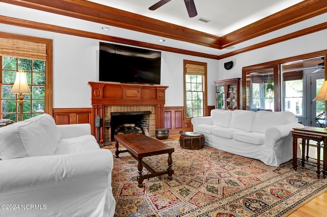 living room featuring ceiling fan, a wealth of natural light, a fireplace, and light hardwood / wood-style floors